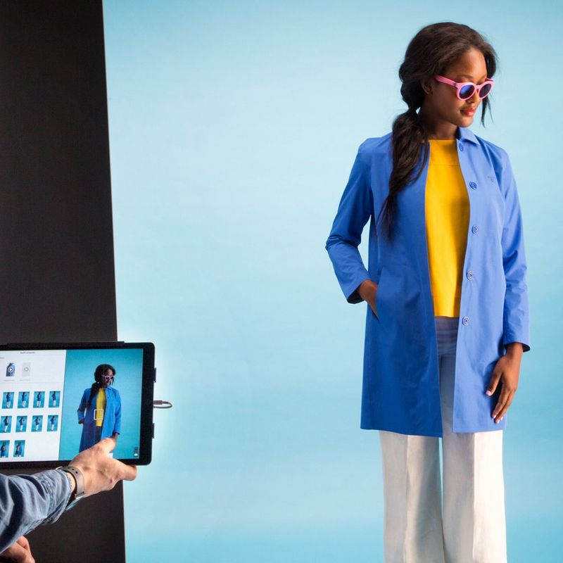 A model in sunglasses and a blue coat being photographed in a StyleShoots photography machine.