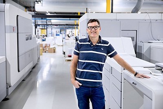 Male standing next to large printing machine
