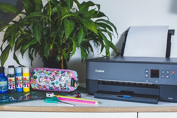 A Canon PIXMA TS5350 Series printer on a desk next to a pencil case and stationery.