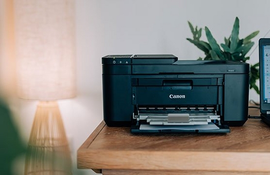 A Canon PIXMA printer on a desk in a home office.