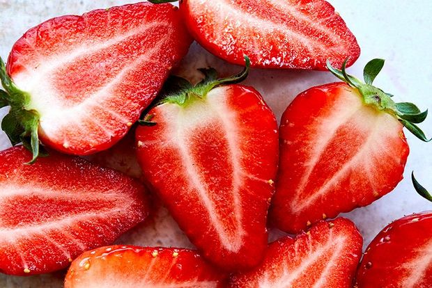 A close-up of halved strawberries on a marble-effect surface.