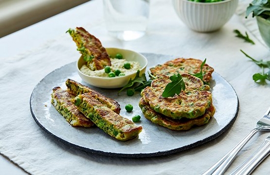 A plate of pea fritters garnished with peas and rocket leaves.