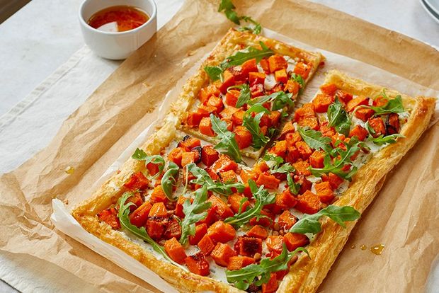 A butternut squash flan garnished with rocket on a sheet of baking paper.