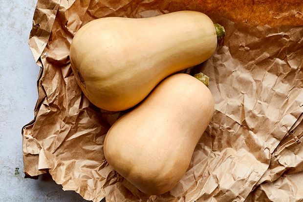 Two butternut squash on a crumpled sheet of brown paper.