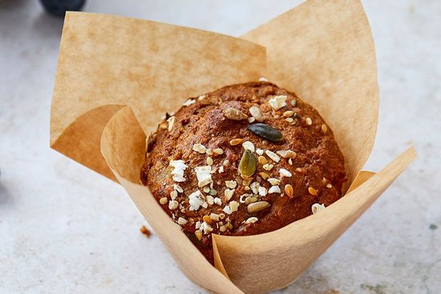 A close-up of a tray of blueberry muffins individually wrapped in brown paper.