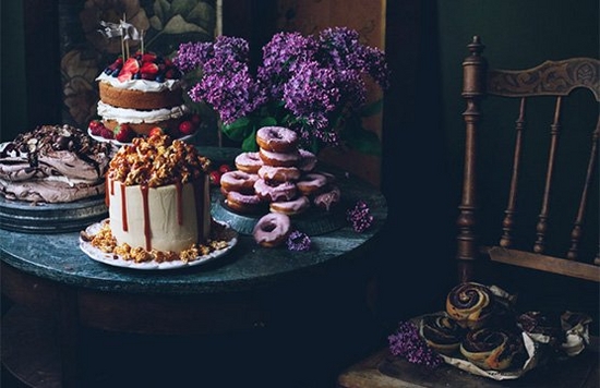 A table display with cakes, meringue, iced donuts and pastries.