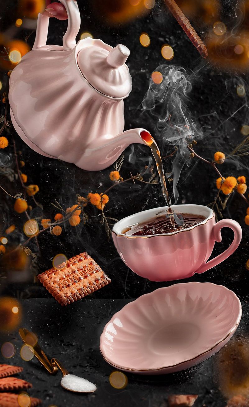 إبريق شاي باللون الوردي يصب الشاي في فنجان يبدو معلقًا في الهواء فوق صحن الفنجان.