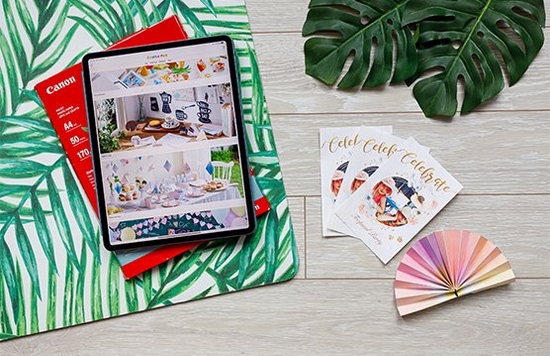 A tablet displaying the Creative Park app sits on botanical themed paper, next to custom invitations and colourful bunting. 