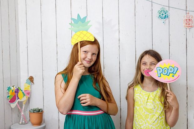 Two girls hold photo booth party props printed from Creative Park