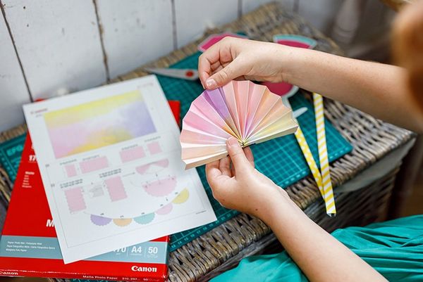 A girl folds a paper party garland printed from the Creative Park app.