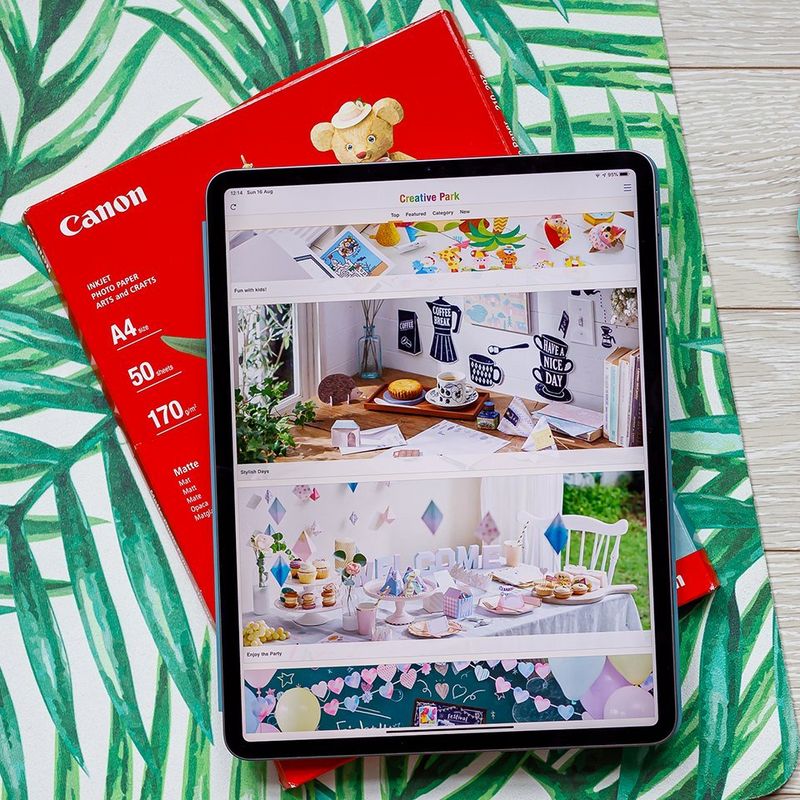 A tablet with Creative Park app open on it lying on the pack of Canon Matte Photo paper.