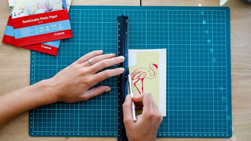 A printed graphic of a flamingo being cut out on a green cutting mat. 