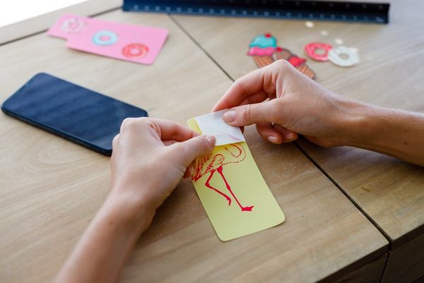 A person peeling a printed sticker off the backing paper. 