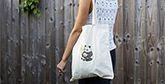 A woman wears a cotton tote bag, adorned with an iron-on transfer of a panda. 