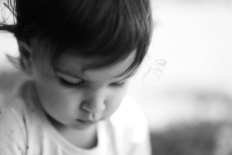 صورة مقربة بالأبيض والأسود لطفل ينظر إلى أسفل بتركيز.