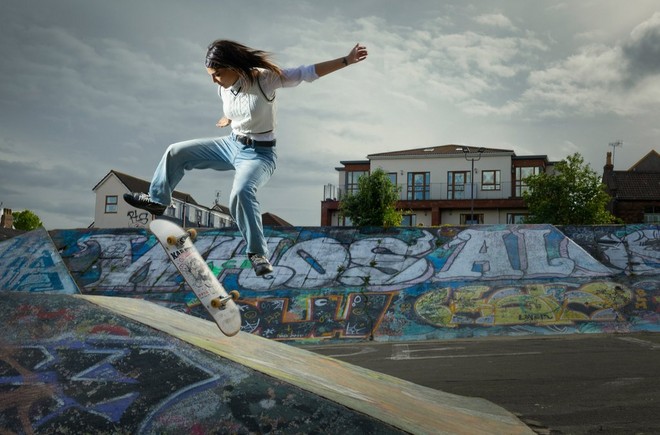Девушка на скейтборде, запечатленная во время прыжка с переворотом доски.