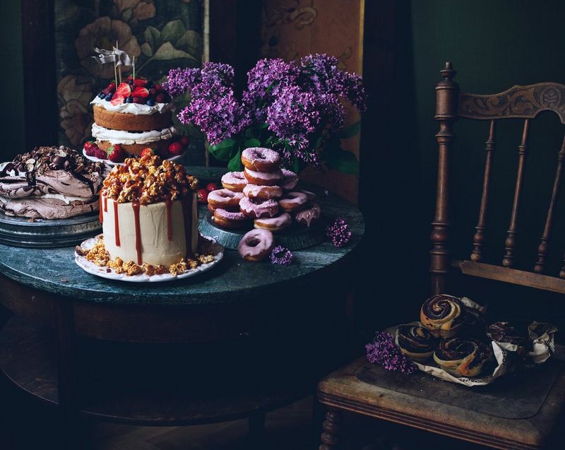 A table display with cakes, meringue, iced donuts and pastries. 