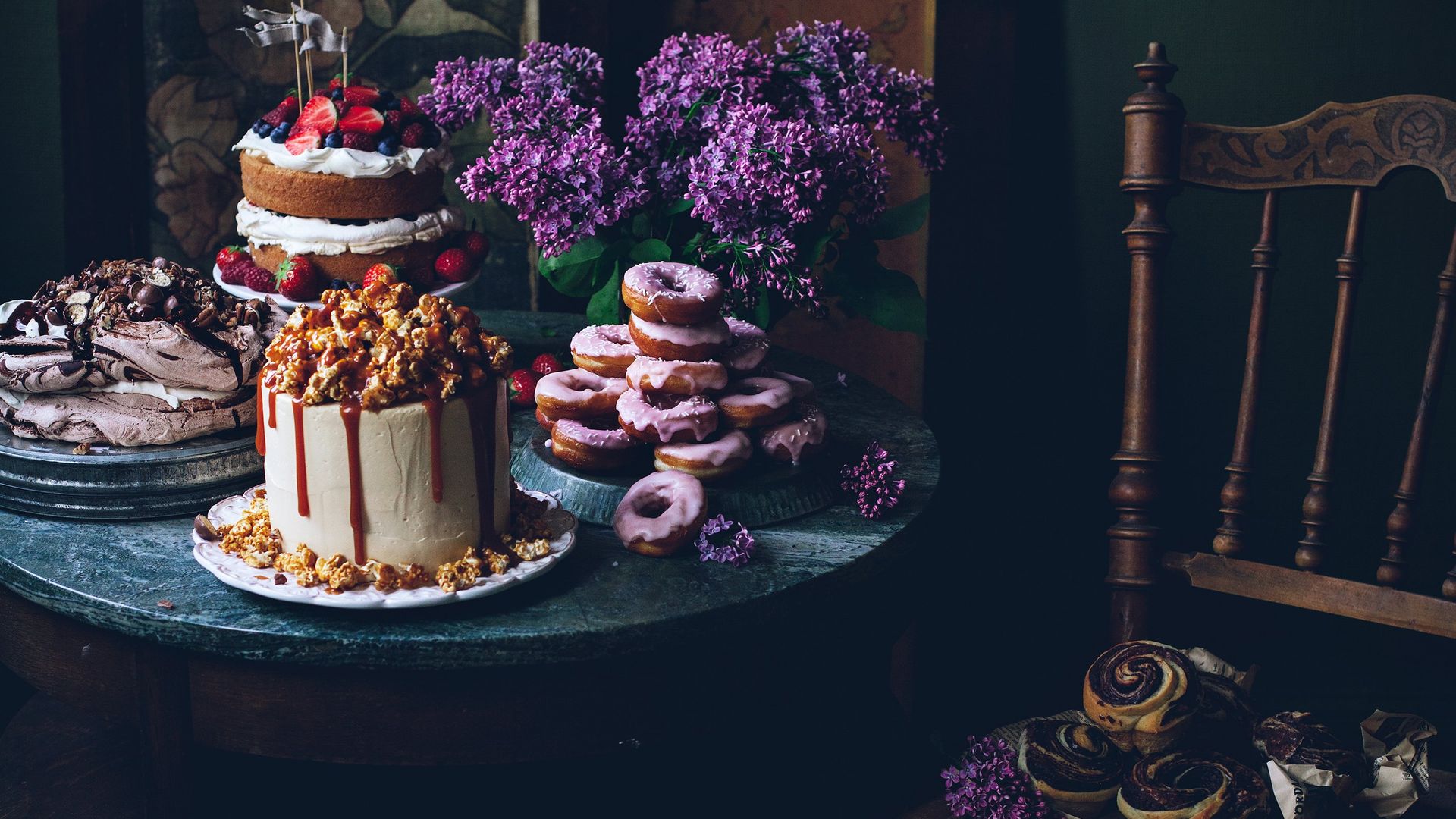A table display with cakes, meringue, iced donuts and pastries. 