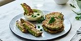 A plate of pea fritters garnished with peas and rocket leaves.
