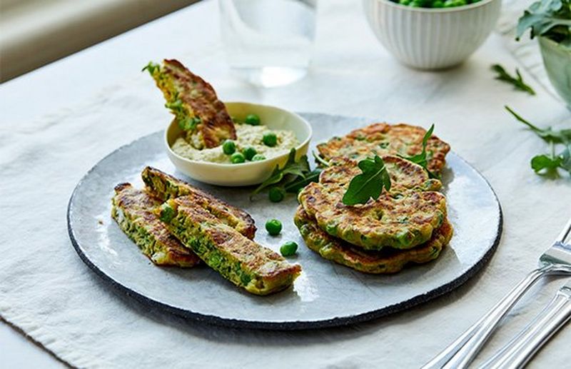 A plate of pea fritters garnished with peas and rocket leaves.