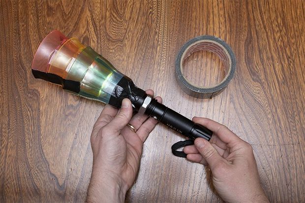 A torch with different coloured cups taped to the end.