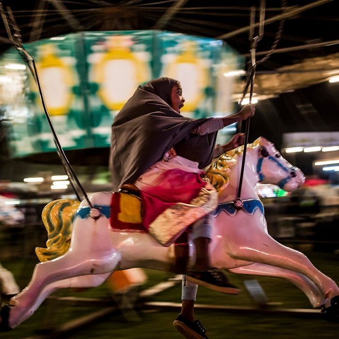 A young Muslim girl shouts with delight as she rides a horse on a carousel at a fete in Johannesburg, South Africa.