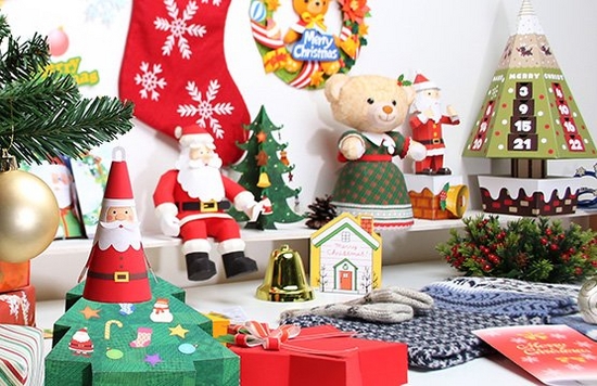 A table is filled with Christmas-themed paper crafted decorations and gifts.