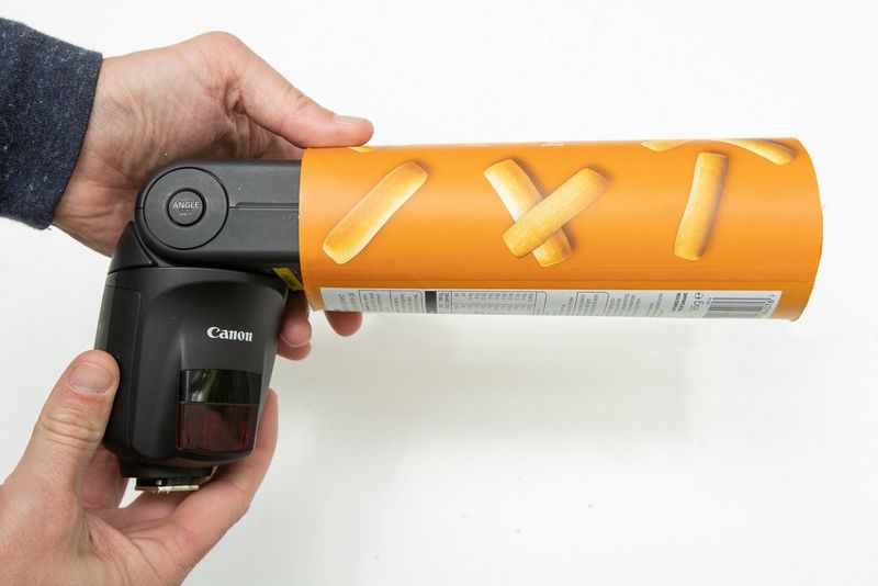 Un homme fait glisser le tube de gâteaux apéritifs sur un flash Speedlite.