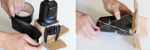 Two hands use black tape to secure a cardboard sheath around a Speedlite flash.
