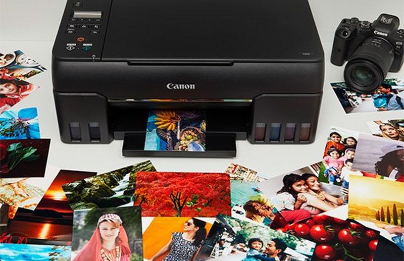 A Canon PIXMA G540 printer surrounded by colourful 4x6 printed photographs.