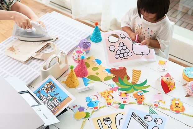 Woman and child's hands on desk filled with creative nick-nacks.