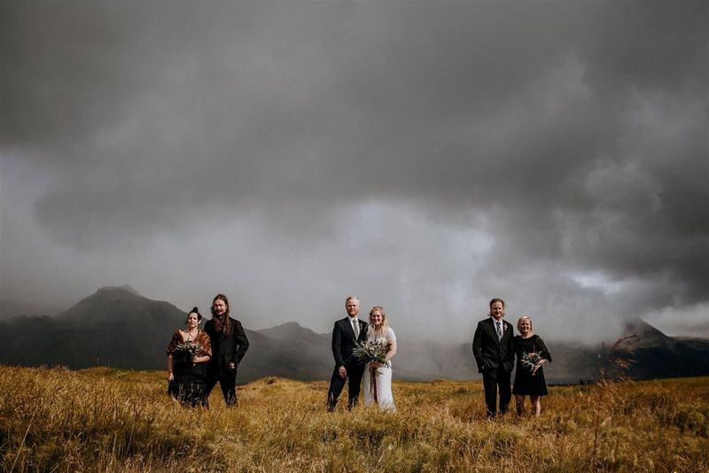 Three couples stand several metres apart in a rugged landscape.