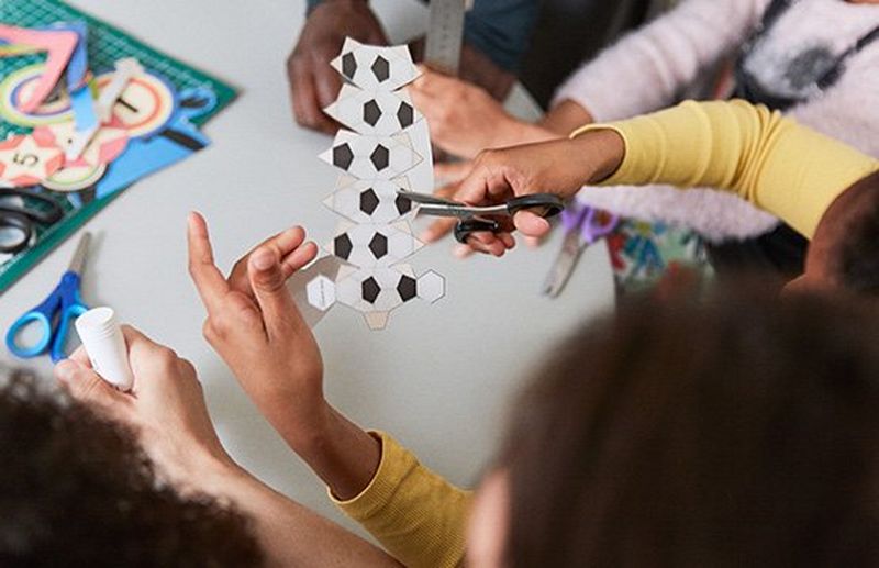 A little girl cutting out a template to make a papercraft football.