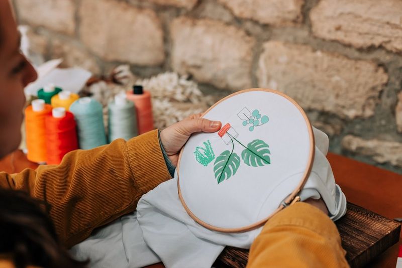 A woman placing a plant-patterned T-shirt in an embroidery hoop.