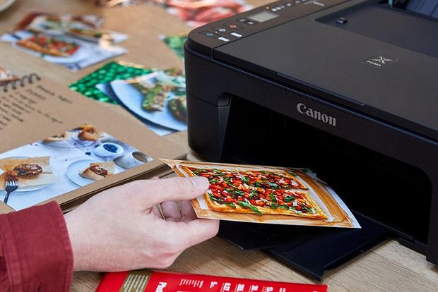 A PIXMA printer prints an image of a sweet potato tart. A child takes the image from the printer.