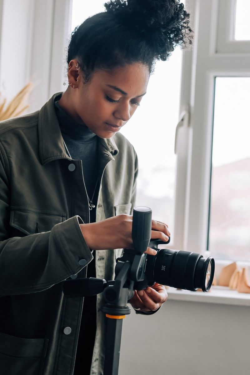 A woman adjusting her EOS 850D on a tripod.