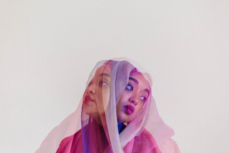 A layered portrait image showing Amaal Said in a pink headscarf, looking in two directions.