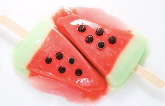 Two ice creams designed to look like slices of watermelon, melting on a plate.