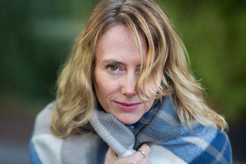 A woman gathers a blanket close to her.