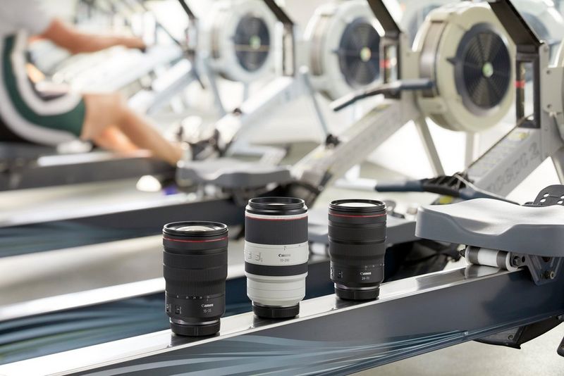 Three zoom lenses stand next to each other on a piece of gym equipment.