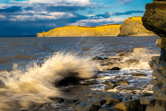 Kis hullámok csapódnak a tengerparton álló szikláknak.