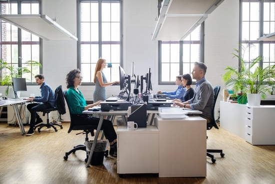 Colleagues face each other while working at computers in the office