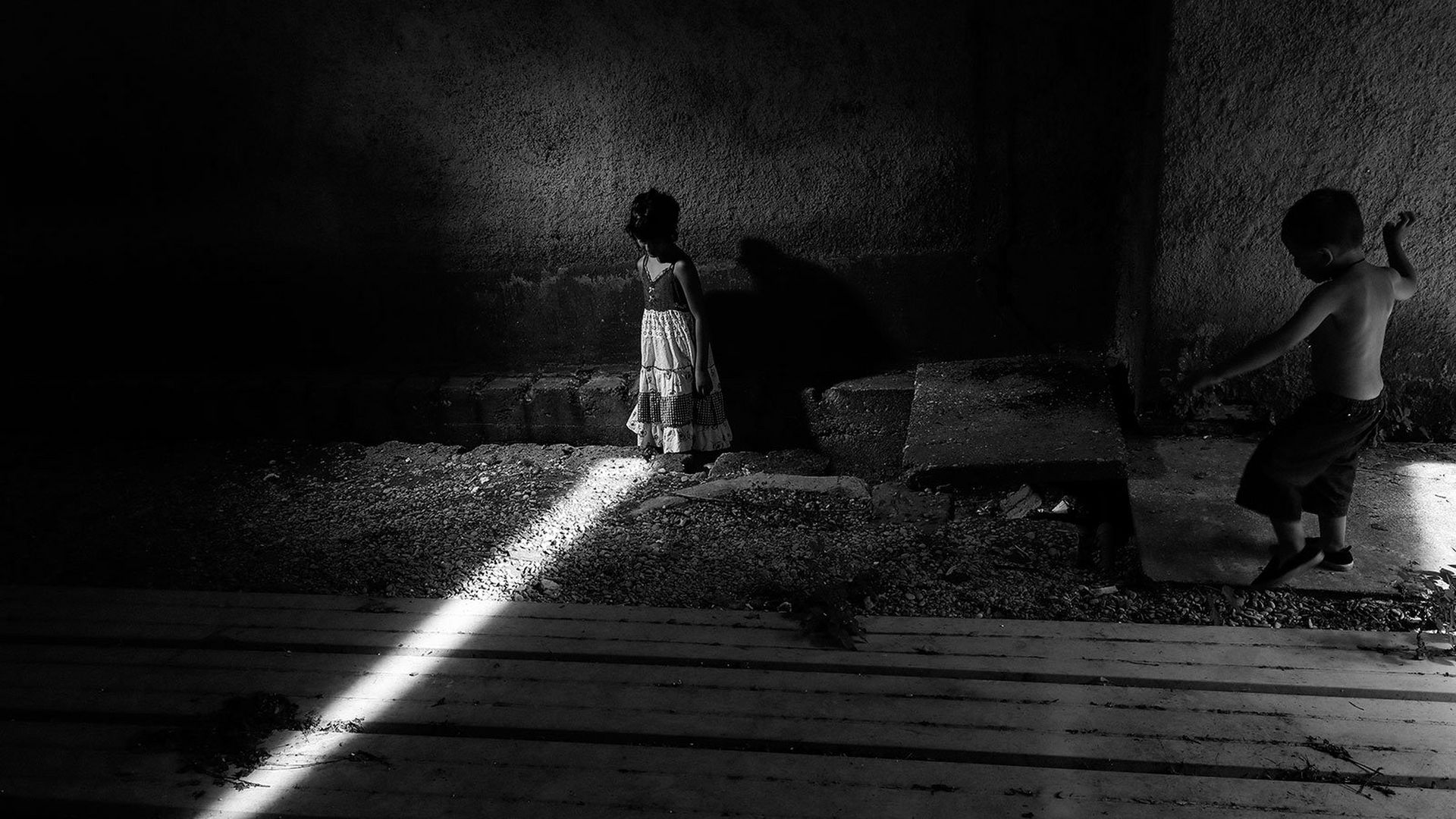 Young gypsy child stands in a shaft of light