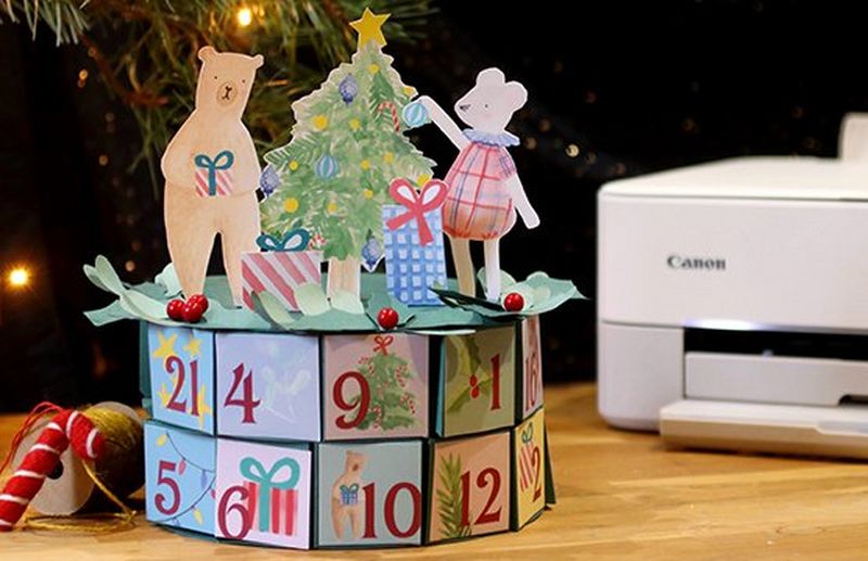 Imprimante Canon PIXMA sur une table en bois avec calendrier de l’Avent de Happy as a Bee et du Papier Photo autocollant repositionnable.