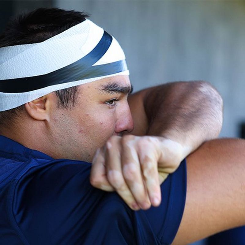 Ein Rugbyspieler im Profil mit bandagiertem Kopf blickt nach rechts