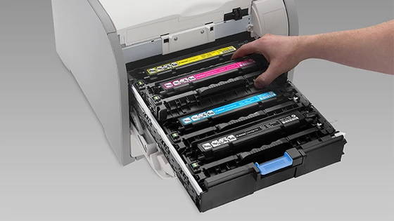 A Canon laser printer with the toner shelf open and a magenta toner being inserted.