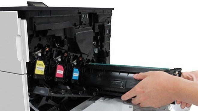 A Canon laser printer with the toner shelf open and the black toner being inserted.