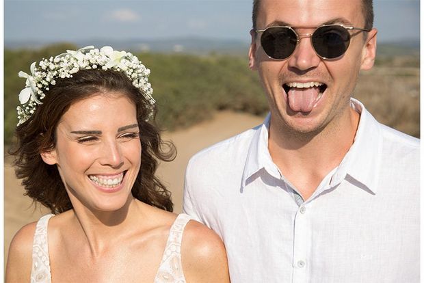 A candid shot of a bride and groom on a beach pulling funny faces.