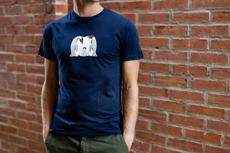 A man wears a dark t-shirt customised with an iron-on transfer of a family of penguins.