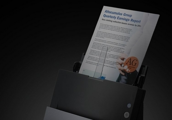 A company’s quarterly earnings report is put through a document scanner, contrasted with a black background.
